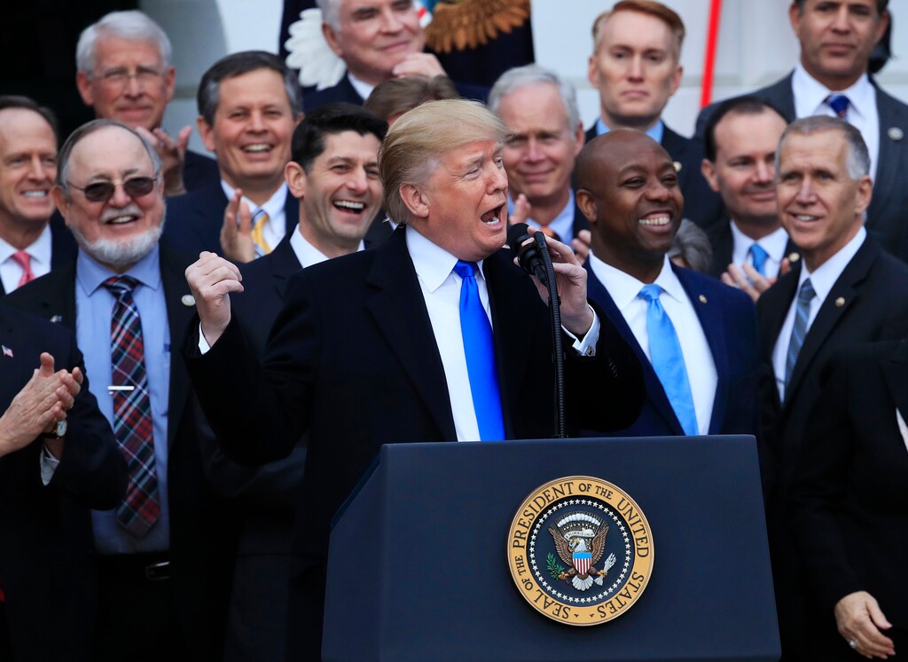 FILE - In this Dec. 20, 2017, file photo, House Speaker Paul Ryan of Wis., back left center, and other lawmakers react as President Donald Trump speaks about the passage of the tax overhaul bill on the South Lawn at the White House in Washington. Trump often brags that he’s done more in his first year in office than any other president. That’s a spectacular stretch. But while he’s fallen short on many measures and has a strikingly thin legislative record, Trump has followed through on dozens of his campaign promises, overhauling the country’s tax code, changing the country’s posture abroad and upending the lives of hundreds of thousands of immigrants. (AP Photo/Manuel Balce Ceneta, File)