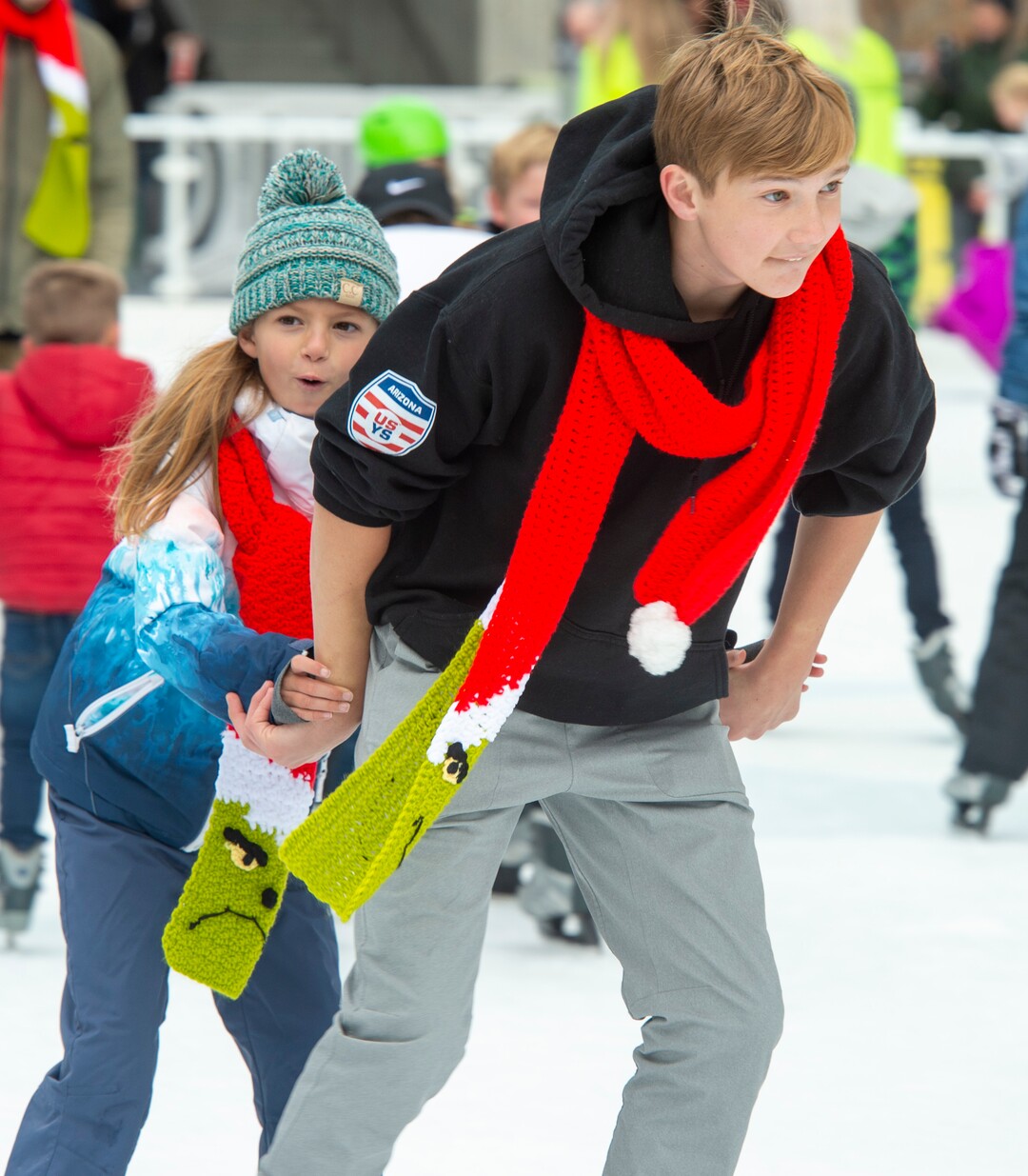 (Rick Egan  |  The Salt Lake Tribune)   
Ruby Nikkel skates with Mattie Habovstak, at the Gallivan Center, on Christmas Eve, Tuesday, Dec. 24, 2019.  Their family has been ice skating on Christmas Eve for the past 35 years.   They are wearing Grinch scarves made by Diane Kortbawi, so she can tell them apart from the other skaters during their annual family ice skating outing.