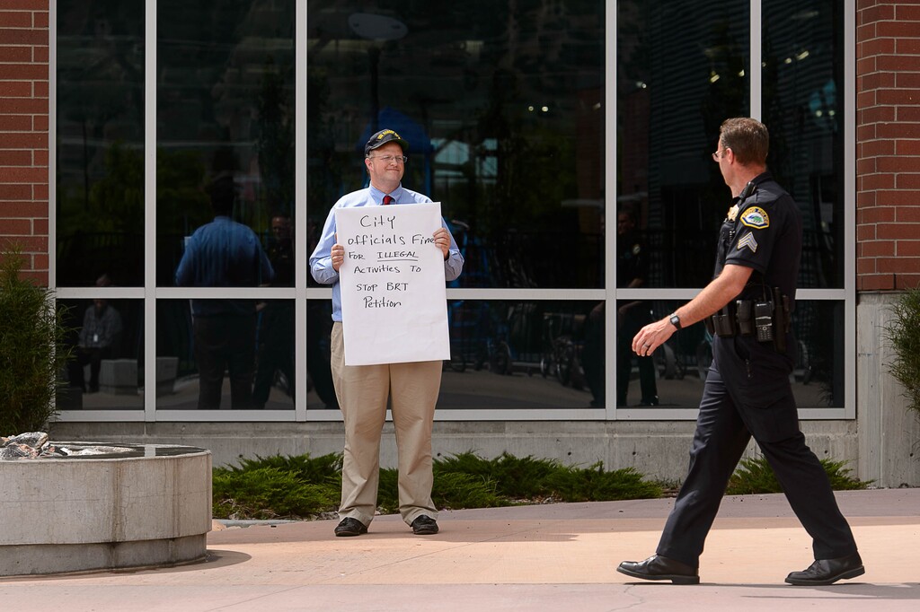 (Trent Nelson  |  The Salt Lake Tribune) Gove Allen holds a protest sign on the grounds of the Provo Recreation Center in Provo, Thursday June 2, 2016. People pushing a petition seeking to stop a controversial transit project said then that the police have been chasing them off public property at the Provo Recreation Center. Groups have now abandoned legal challenges of that project.