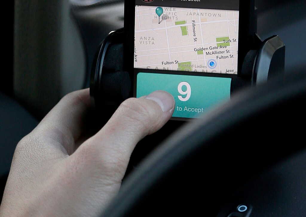 (Jeff Chiu | AP file photo) In this Jan. 4, 2013, file photo, Lyft driver Nancy Tcheou uses her phone to accept a ride from a passenger in San Francisco. The rise of on-demand apps and services are bringing up questions on what to tip drivers, Instacart grocery delivery people and others.