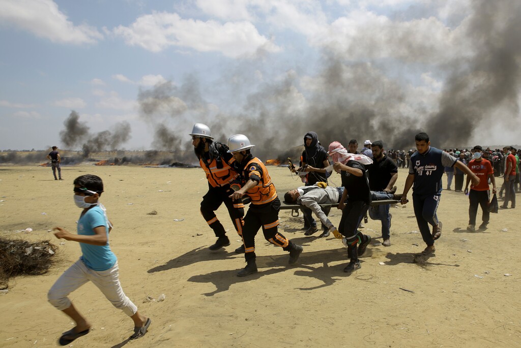 (Adel Hana | The Associated Press) Palestinian medics and protesters evacuate a wounded youth during a protest at the Gaza Strip's border with Israel, east of Khan Younis, Gaza Strip, Monday, May 14, 2018. Thousands of Palestinians are protesting near Gaza's border with Israel, as Israel prepared for the festive inauguration of a new U.S. Embassy in contested Jerusalem.