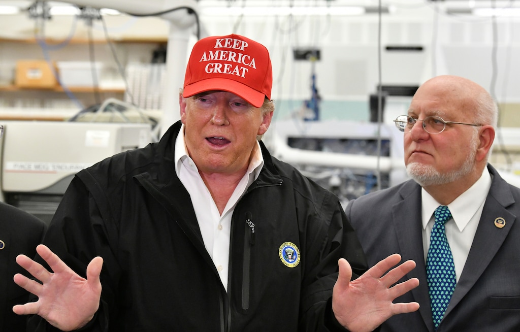 President Donald Trump speaks to members of the press as Director Robert Redfield, right, looks at the headquarters of the Centers for Disease Control and Prevention in Atlanta on Friday, March 6, 2020. President Trump's trip to the Centers for Disease Control and Prevention, briefly scuttled Friday because of unfounded fears that someone there had contracted the coronavirus, was back on, giving the president another chance to calm growing alarm about the spread of the virus in America. (Hyosub Shin/Atlanta Journal-Constitution via AP)