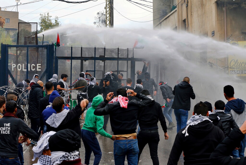 (Bilal Hussein | Associated Press) Protesters try to enter the U.S. Embassy as they are sprayed by riot police using water cannons during a demonstration in Aukar, east of Beirut, Lebanon, Sunday, Dec. 10, 2017. A few hundred demonstrators, including Palestinians, pelted security outside the embassy with stones and burned an effigy of U.S. President Donald Trump in a protest to reject Washington's recognition of Jerusalem as capital of Israel.