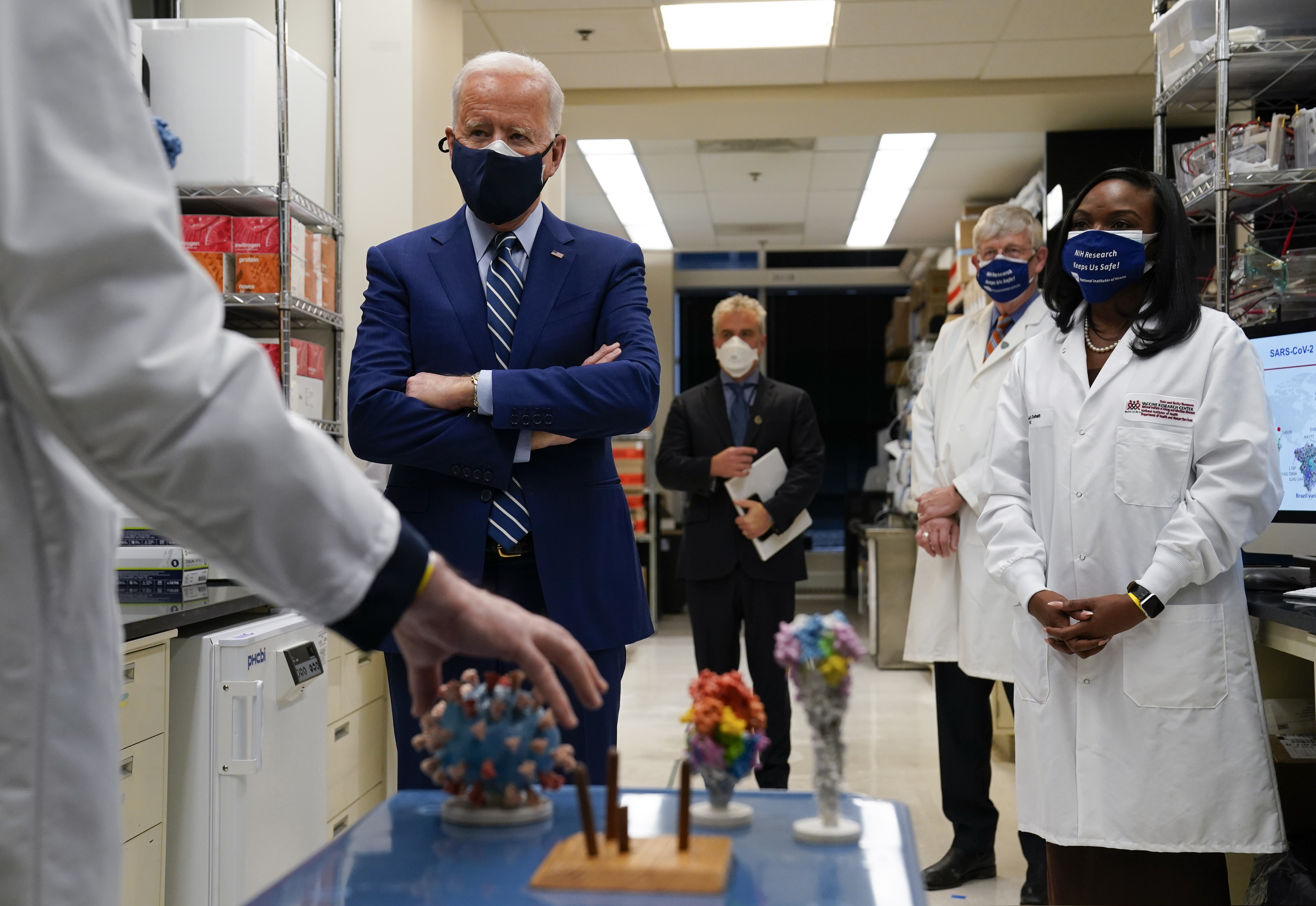 Dr. Barney Graham, left, speaks as President Joe Biden listens during a visit to the Viral Pathogenesis Laboratory at the National Institutes of Health (NIH), Thursday, Feb. 11, 2021, in Bethesda, Md. Kizzmekia Corbett, an immunologist with the Vaccine Research Center at the NIH, right, and NIH Director, second from right, listen. (AP Photo/Evan Vucci)