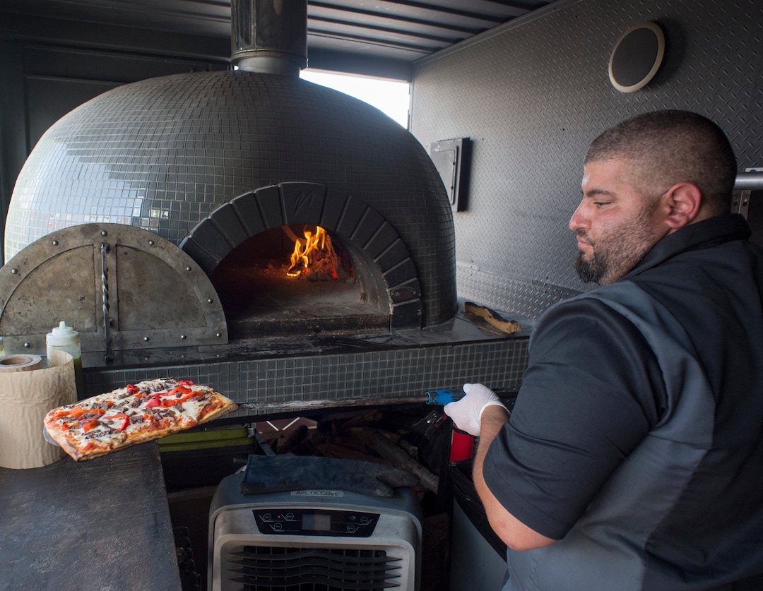 (Rick Egan  |  The Salt Lake Tribune) Fabio Marsenro removes a square pizza from the 4,000-pound wood-fired oven inside the Umani food truck.