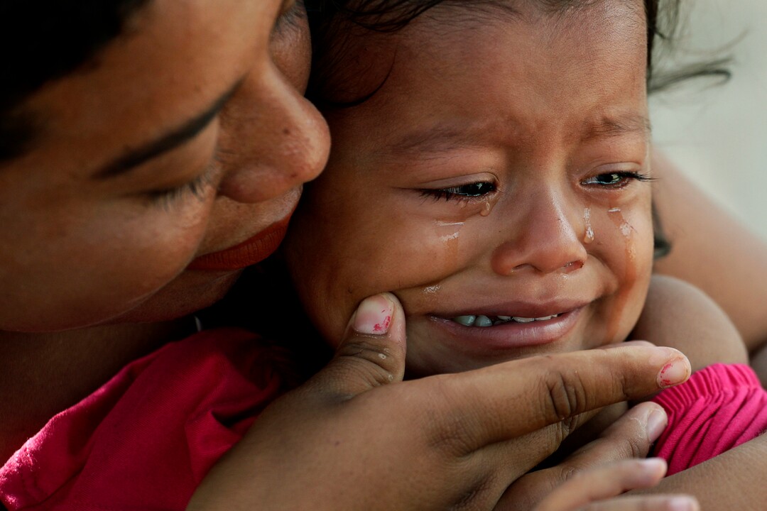 In this Tuesday, Nov. 5, 2019, photo, a migrant child's tears are wiped away by her mother as they receive medical care at a sidewalk clinic in refugee camp in Matamoros, Mexico. The few doctors and nurses working in the camp are treating people including pregnant women and children with respiratory problems, skin conditions, diarrhea, and other diseases that can be linked to the camp’s unsanitary conditions. (AP Photo/Eric Gay)