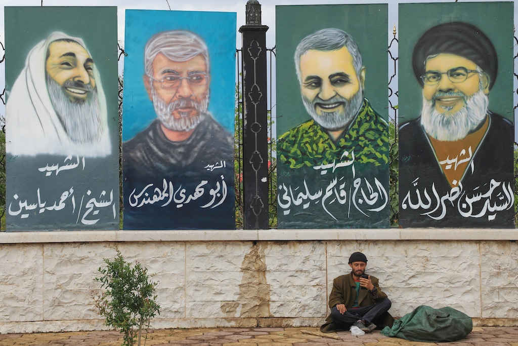 A man sits under posters showing (from right to left) "martyrs" — Hezbollah's top leader Hassan Nasrallah; former Islamic Revolutionary Guard Corps (IRGC) major general Qassem Soleimani; deputy commander of the Popular Mobilization Forces Abu Mahdi al-Muhandis; and Sheik Ahmed Yassin, founder of Islamic group Hamas — in Sanaa, Yemen, Tuesday, March 31, 2026. (AP Photo/Osamah Abdulrahman)
