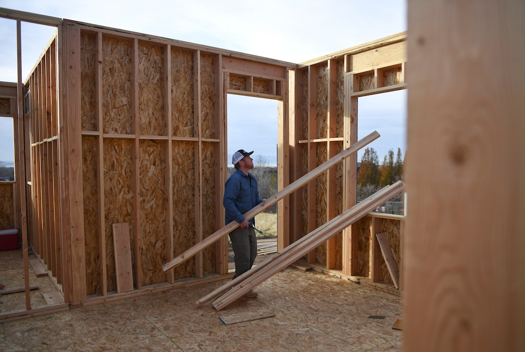 In this Nov. 10, 2017, photo, Dustin Brinkerhoff, owner of Brinkerhoff Custom Construction, walks with boards to put in place as a temporary safety guard rail at a worksite of a future home in Mapleton, Utah. According to research by Ken Simonson, the chief economist for the Associated General Contractors of America, the construction industry is generally very robust. Utah sits in the middle of the pack, adding about 4,000 jobs in the past year. Brinkerhoff sees effects of labor shortage in "every job, every day." (Isaac Hale/The Daily Herald via AP)