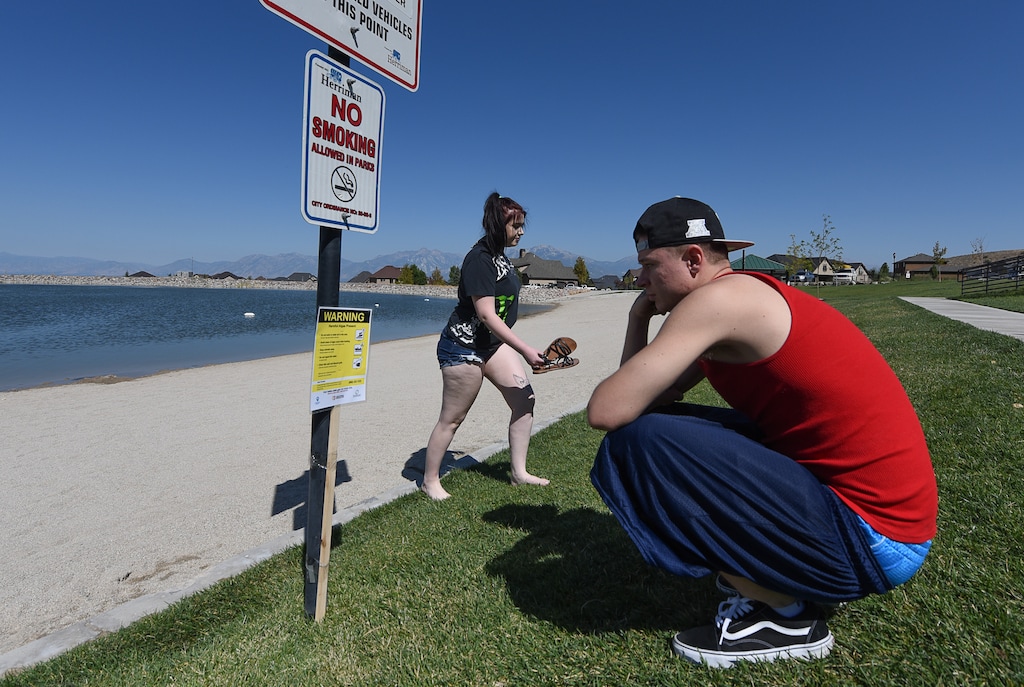 (Francisco Kjolseth | The Salt Lake Tribune) Shelby Morgan and Kyle Jones read the warning signs that have been posted at the popular Black Ridge Reservoir in Herriman on Tuesday, Aug. 28, 2018, where an outbreak of algae-related toxin cyanobacteria was detected in the water.
