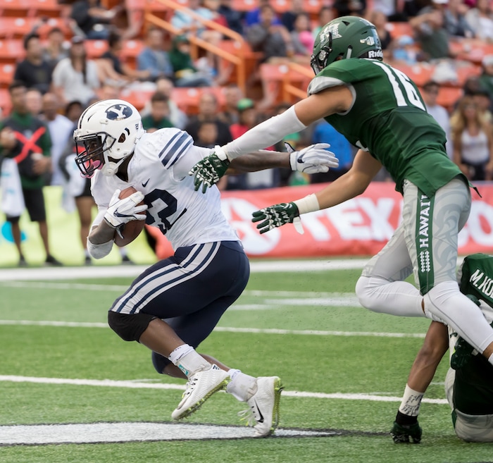 BYU running back Squally Canada, left, scores a touchdown while being defended by Hawaii defensive back Kalen Hicks (16) in the second quarter of an NCAA college football game, Saturday, Nov. 25, 2017, in Honolulu. (AP Photo/Eugene Tanner)