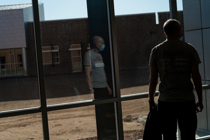 Team Rubicon volunteer Dr. Stan Chartoff, U.S. Air Force Reserve from Hartford, Conn., is reflected in the window as he walks to the emergency department of the Kayenta Health Center on the Navajo reservation in Kayenta, Ariz., on April 19, 2020. The reservation has some of the highest rates of coronavirus in the country. Team Rubicon is helping with medical operations as cases of COVID-19 surge. (AP Photo/Carolyn Kaster)