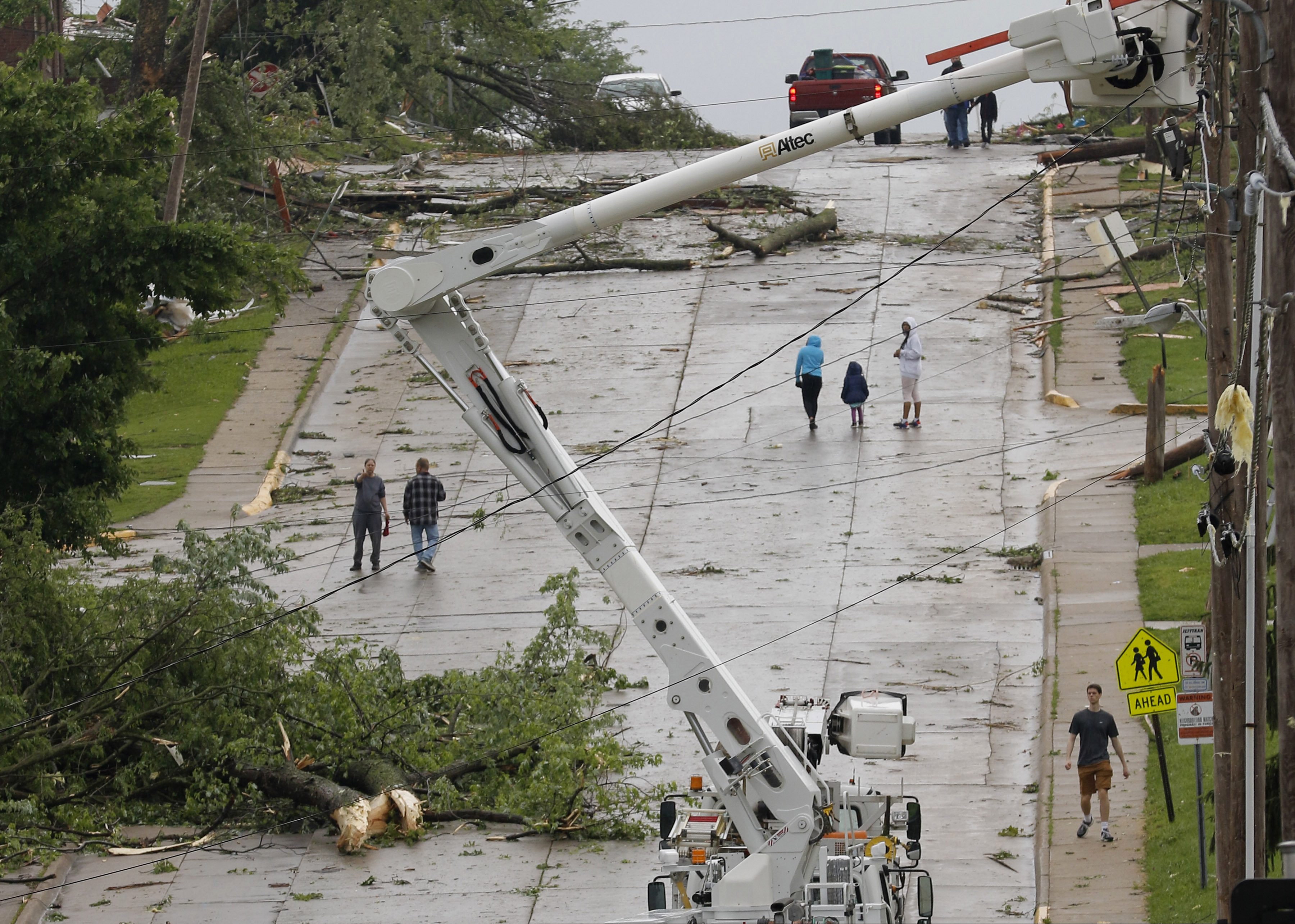 (Liv Paggiarino/Missourian via AP) People walk up Dunklin Street on Thursday, May 23, 2019, in Jefferson City, Mo. The early analysis of storm damage has led the National Weather Service to believe the town was struck by an EF3.