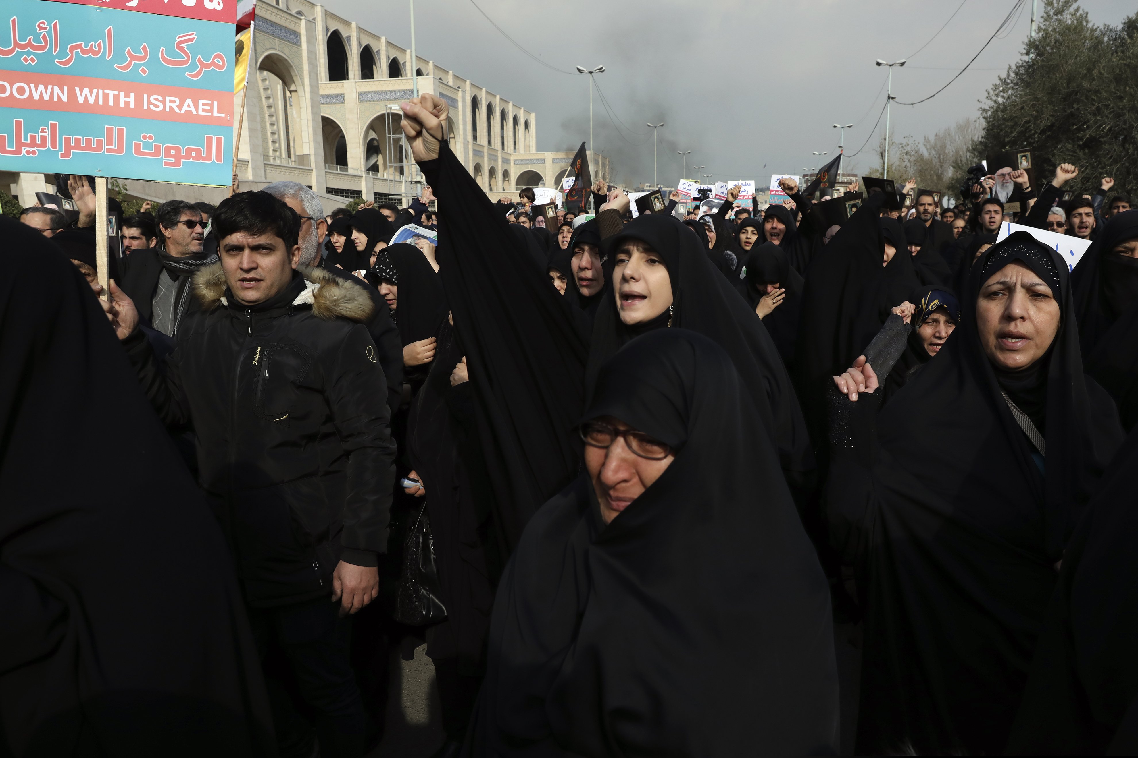 (Vahid Salemi | AP) A woman clenches her fist as she chants slogan while a man holds an anti-Israeli placard during a demonstration over the U.S. airstrike in Iraq that killed Iranian Revolutionary Guard Gen. Qassem Soleimani in Tehran, Iran, Jan. 3, 2020. Iran has vowed "harsh retaliation" for the U.S. airstrike near Baghdad's airport that killed Tehran's top general and the architect of its interventions across the Middle East, as tensions soared in the wake of the targeted killing.