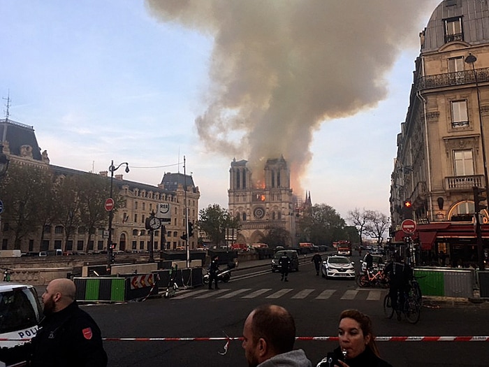 Notre Dame cathedral is burning in Paris, Monday, April 15, 2019. Massive plumes of yellow brown smoke is filling the air above Notre Dame Cathedral and ash is falling on tourists and others around the island that marks the center of Paris. (AP Photo/Lori Hinant)
