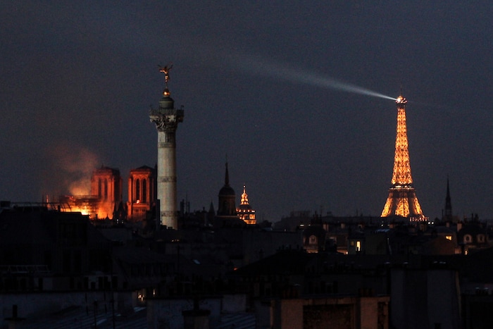 15 April 2019, France (France), Paris: The Paris cathedral Notre-Dame (l) is illuminated by a glow of fire. A fire broke out in the world-famous cathedral Notre-Dame in Paris on Monday evening. Above the landmark there were flames and a huge column of smoke. A small pointed tower in the middle of the roof collapsed. Photo by: Matthias Wagner/picture-alliance/dpa/AP Images
