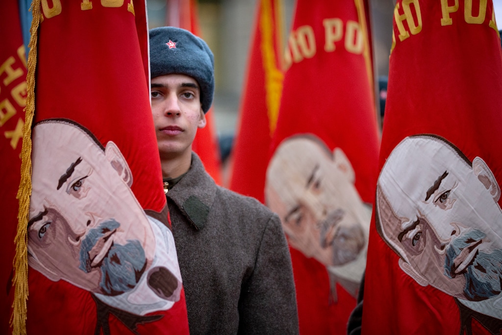 A Russian soldier dressed in Red Army World War II winter uniform stands amid Soviet-era flags as he waits to take part in a reconstruction of a World War II-era parade in Moscow's Red Square, Russia, Thursday, Nov. 7, 2019. (AP Photo/Alexander Zemlianichenko)