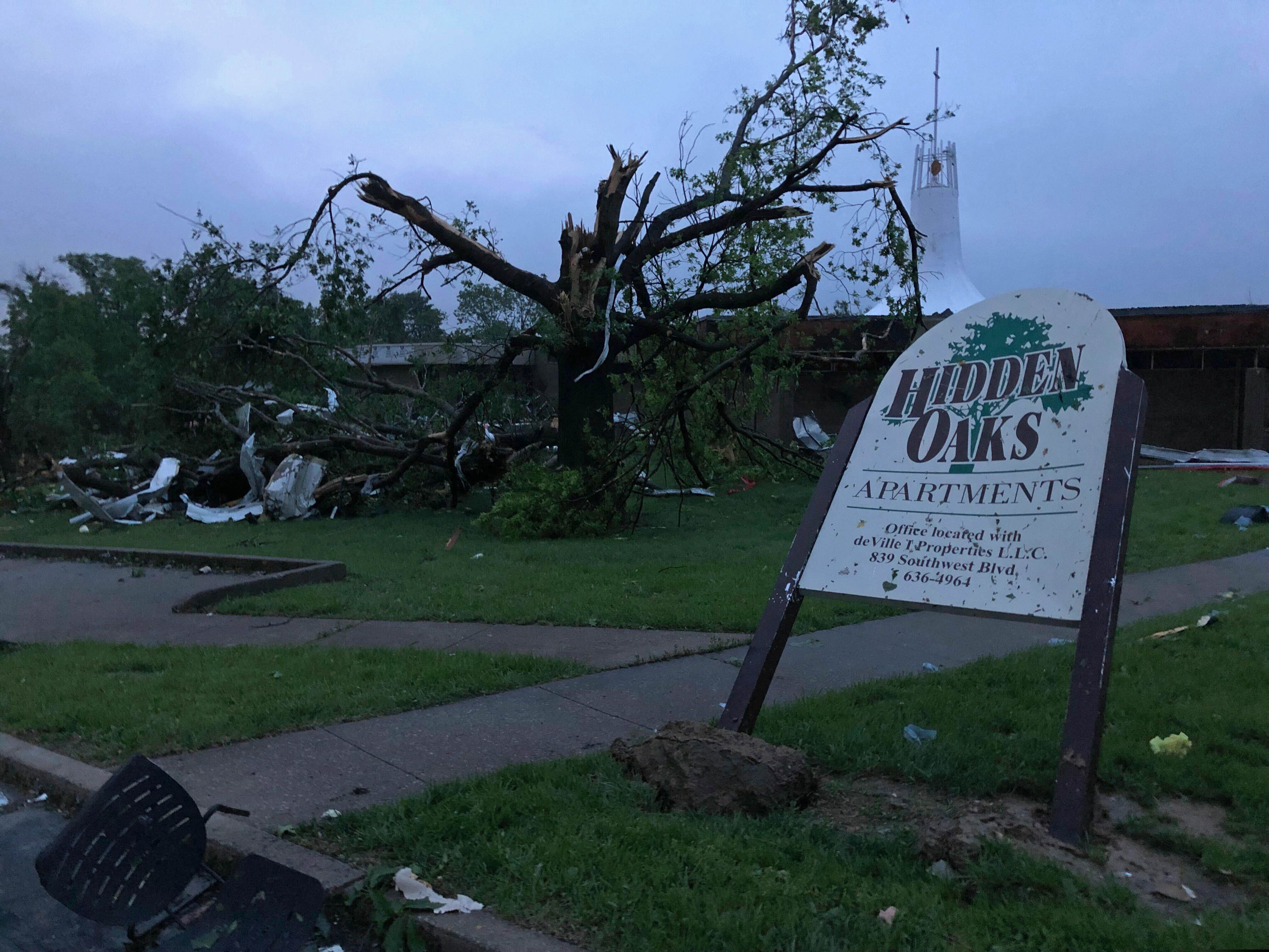 (David A. Lieb | AP) The sign for the Hidden Oaks apartment complex in Jefferson City Missouri stands bent Thursday, May 23, 2019, from a tornado in front of a tree that was ripped apart. The National Weather Service has confirmed a large and destructive tornado has touched down in Missouri's state capital, causing heavy damage and trapping multiple people in the wreckage of their homes.