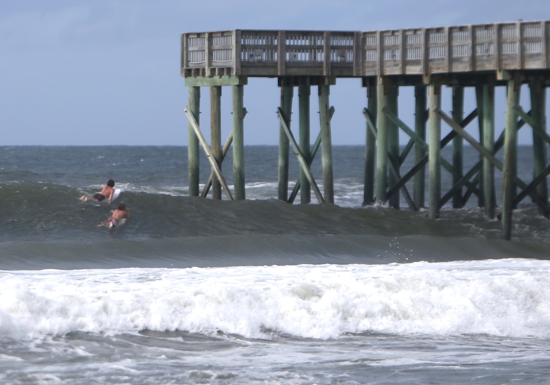 (Patti Blake | News Herald | The Associated Press) Surfers paddle past the St.Andrews State Park Pier Tuesday, Oct.9, 2018,  at Panama City Beach, Fla.