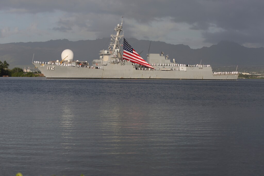U.S. Navy sailors stand on the deck of a ship as it passes through Pearl Harbor on Monday, Dec. 7, 2020, in Pearl Harbor, Hawaii. (AP Photo/Caleb Jones, Pool)