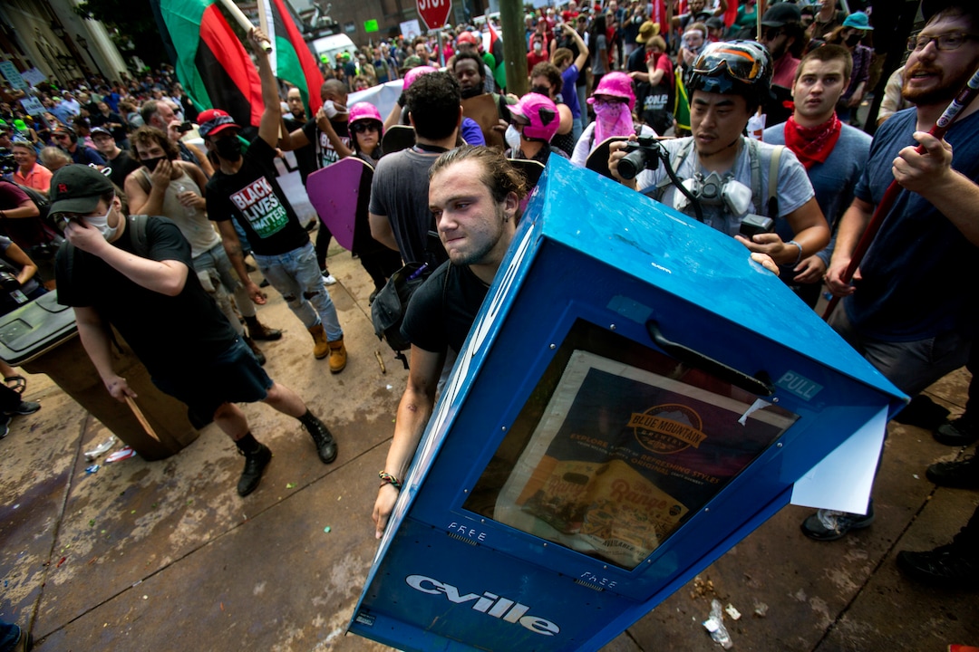 A counter-protester throws a newspaper stand during a white nationalist rally on Saturday Aug. 12, 2017, in Charlottesville, Va. The nationalists had gathered to protest plans by the city of Charlottesville to remove a statue of Confederate Gen. Robert E. Lee. (Shaban Athuman /Richmond Times-Dispatch via AP)