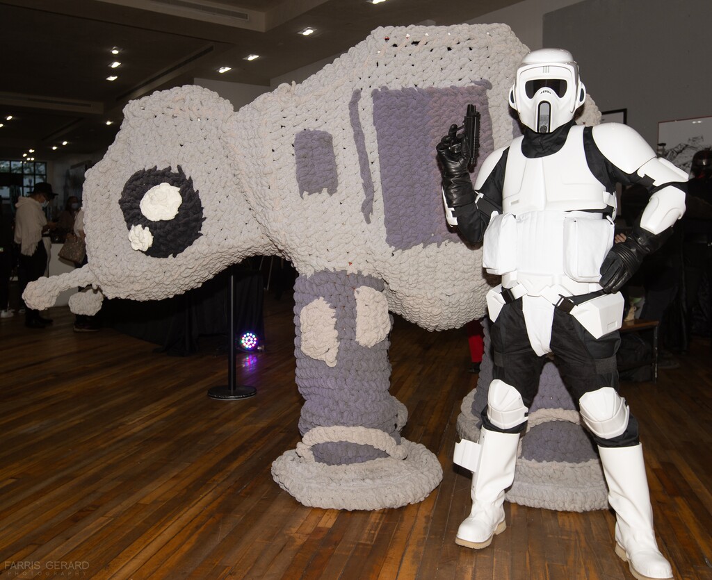 (Faris Gerard | Utah Arts Alliance) A cosplayer in a stormtrooper get-up poses by a crochet version of an AT-AT walker at the Urban Arts Gallery's annual "Star Wars" art exhibition. This year's version launches with a reception on May 4, 2022, at the gallery, at 116 S. Rio Grande, Salt Lake City, in The Gateway shopping center.