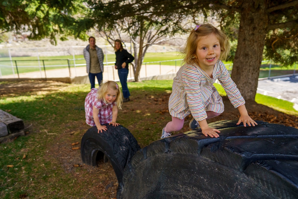 (Trent Nelson | The Salt Lake Tribune) Hope and Ruth Spataro play in a park behind a chapel in Cottonwood Heights on Wednesday, April 21, 2021. The chapel caught fire a few years ago, and the LDS Church wants to sell off the entire property, including the park that neighbors helped build in the 1970s. At rear are Joe and Lyn Spataro.