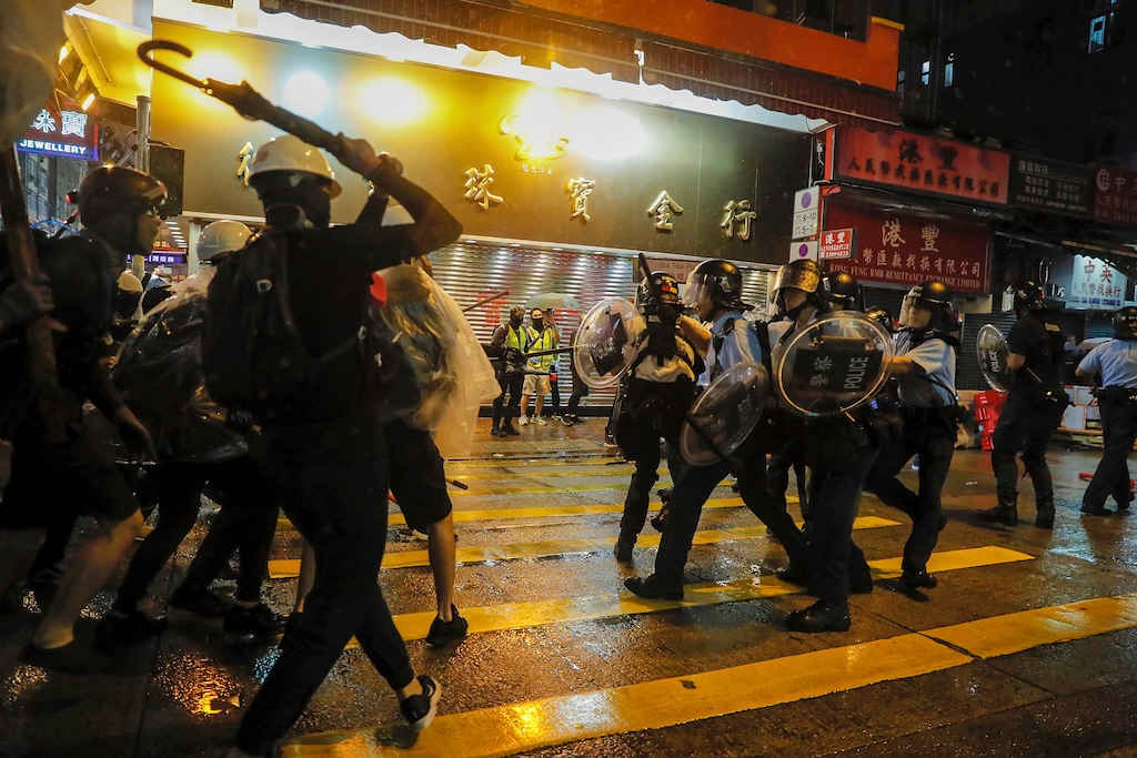 Policemen are confronted by demonstrators on a street during a protest in Hong Kong, Sunday, Aug. 25, 2019. Hong Kong police have rolled out water cannon trucks for the first time in this summer's pro-democracy protests. The two trucks moved forward with riot officers Sunday evening as they pushed protesters back along a street in the outlying Tsuen Wan district. (AP Photo/Kin Cheung)