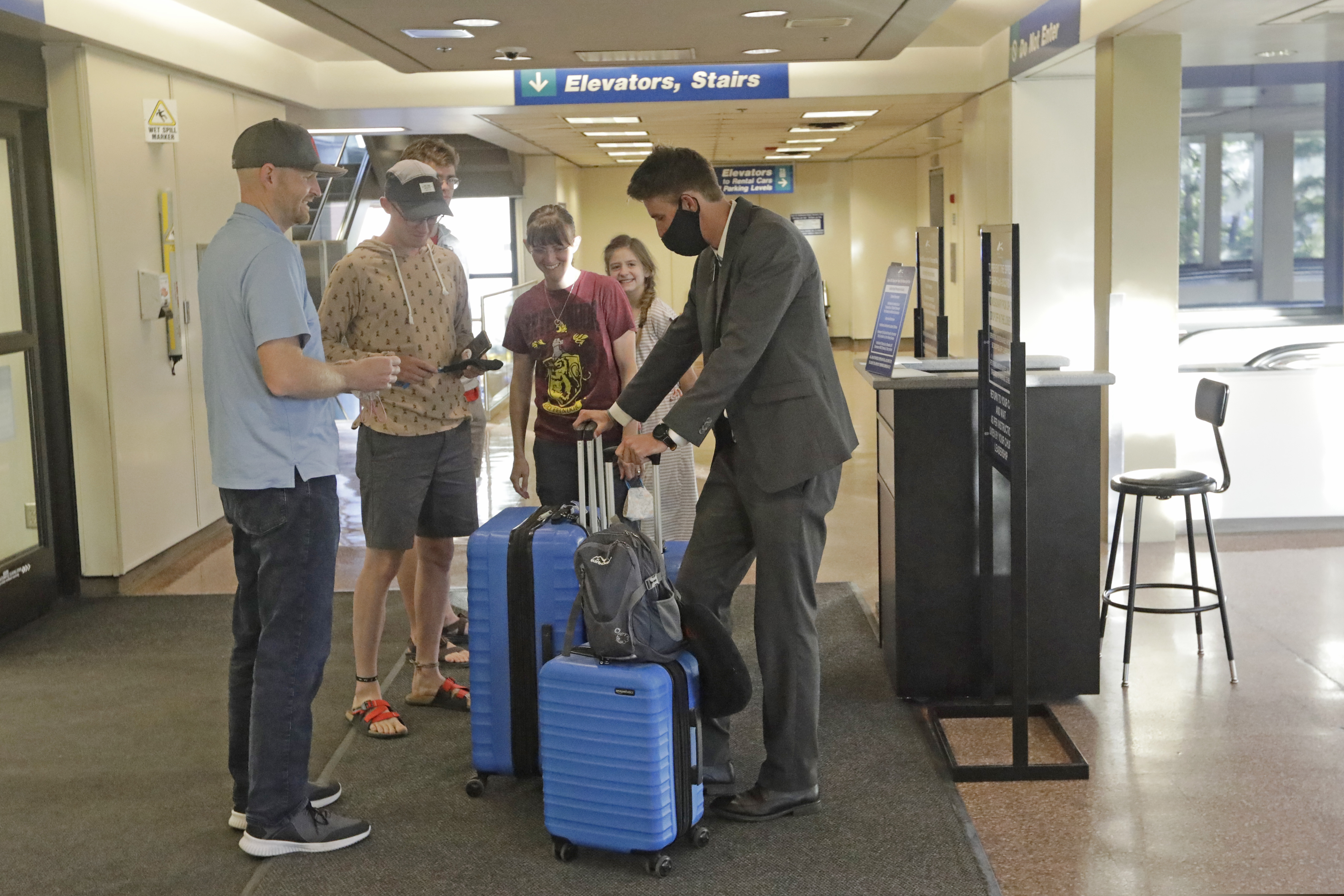 In this May 27, 2020, photo, Logan Morrison, 18, right, a missionary from The Church of Jesus Christ of Latter-day Saints, says goodbye to his family at Salt Lake City International Airport before leaving on his mission to St. Louis. After hastily bringing home 26,000 young men and women who were serving in foreign countries, the faith has begun sending many of them out again in their home countries with a new focus on online work that could stick even when the pandemic is over, church officials told The Associated Press. (AP Photo/Rick Bowmer)