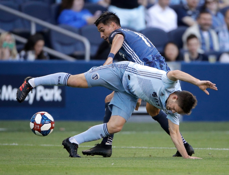 Sporting Kansas City midfielder Kelyn Rowe, front, and LA Galaxy's Favio Alvarez battle for control during the first half of an MLS soccer match Wednesday, May 29, 2019, in Kansas City, Kan. (AP Photo/Charlie Riedel)