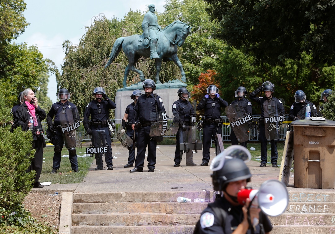 State Police in riot gear guard Lee Park after a white nationalist demonstration was declared illegal and the park was cleared in Charlottesville, Va., Saturday, Aug. 12, 2017.  Hundreds of people chanted, threw punches, hurled water bottles and unleashed chemical sprays on each other Saturday after violence erupted at the white nationalist rally. (AP Photo/Steve Helber)