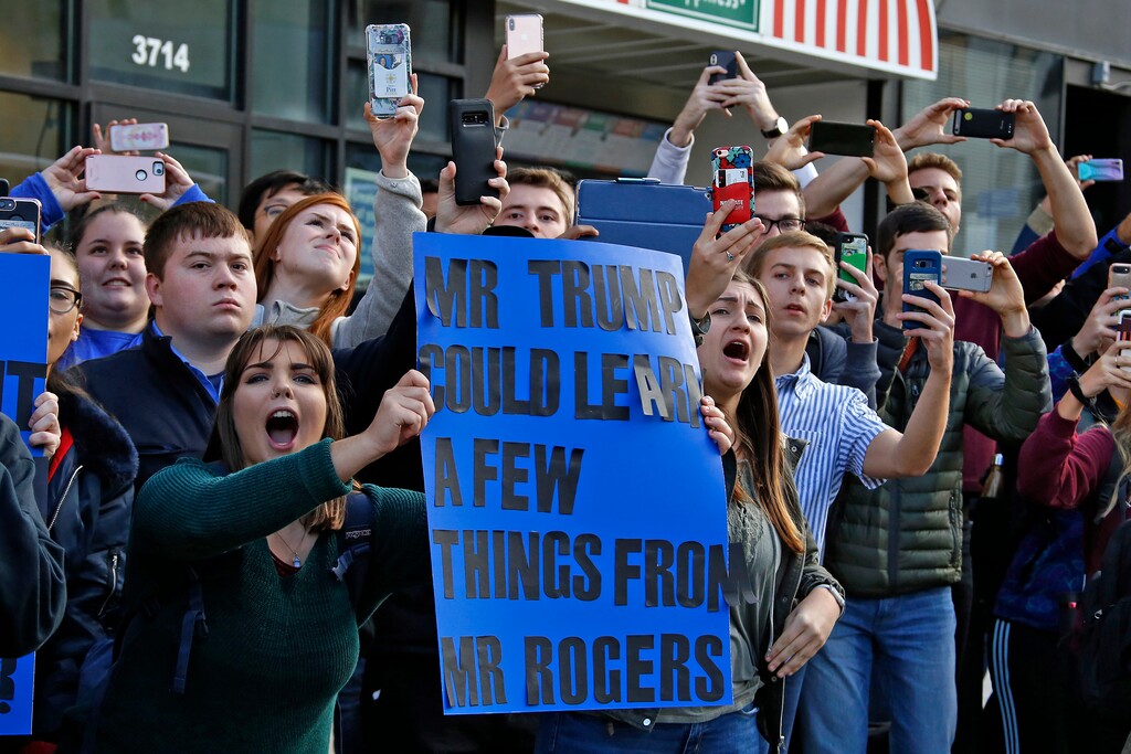 University of Pittsburgh sophomore Lynne Jaworski, from Homer City, Pa., holds a sign and yells as President Donald Trump's motorcade arrives at the University of Pittsburgh's Presbyterian Hospital in Pittsburgh, Tuesday Oct. 30, 2018. President Trump is paying a visit to the Pittsburgh Police who were wounded Saturday, Oct. 27, 2018, when a gunman interrupted worship services at the Tree of Life Synagogue, killing 11, and wounding six. (AP Photo/Gene J. Puskar)