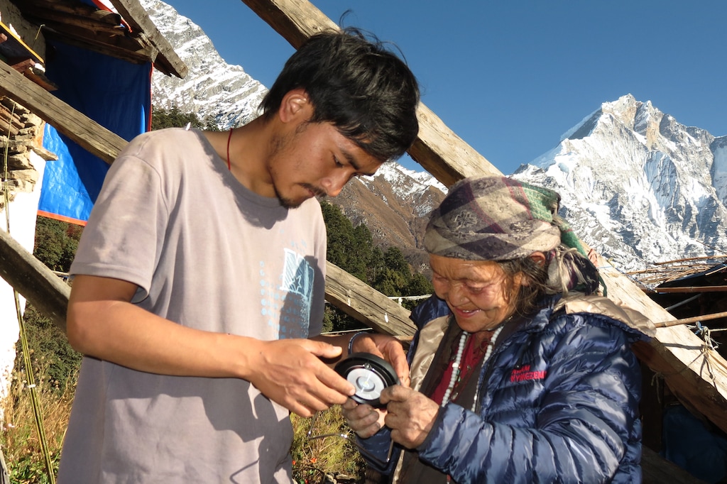 (Sky Chaney) Village Light's board president, Pema Tsumpa, distributes a new solar light to a woman in Nepal.
