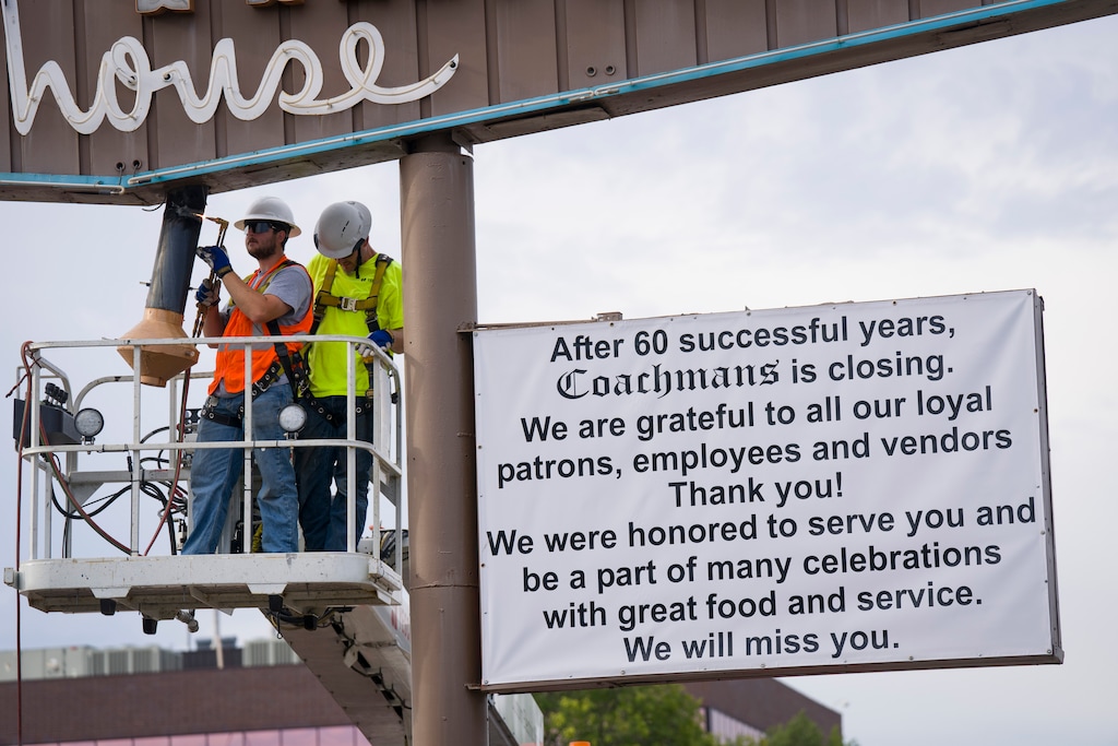 (Bethany Baker  |  The Salt Lake Tribune) Crews work to remove the Coachman's sign in Salt Lake City on Tuesday, July 21, 2026.
