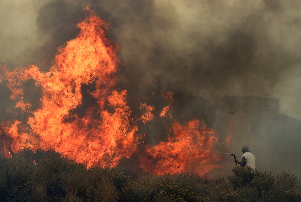 (Jason Bean | The Reno Gazette-Journal via AP) Homeowner Steven Phelps tries to fight the Pinehaven Fire in the Caughlin Ranch area of Reno, Nev., on Tuesday, Nov. 17, 2020.