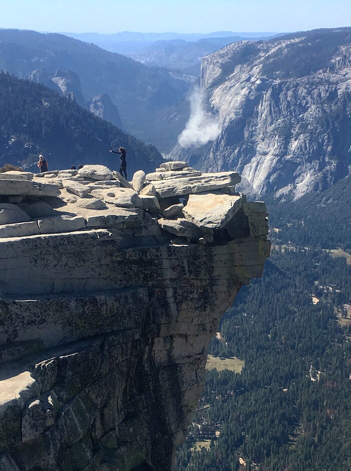 In this Wednesday Sept. 27, 2017, photo provided John P. DeGrazio, a cloud of dust is seen in the distance on El Capitan after a major rock fall in Yosemite National Park, Calif. All areas in California's Yosemite Valley are open Thursday, a day after the fatal rock fall. (John P. DeGrazio/YExplore Yosemite Adventures via AP)