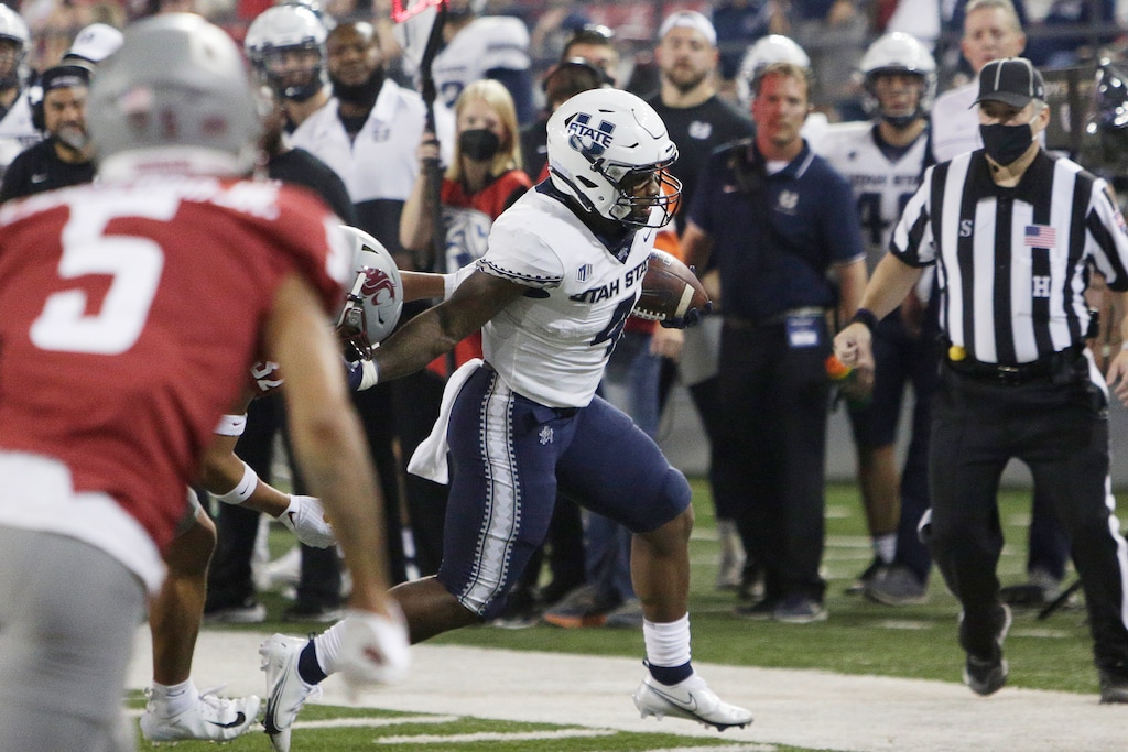 (Young Kwak | AP) Utah State running back Calvin Tyler Jr., right, carries the ball while pressured by Washington State defensive back Tanner Moku, obscured, during the first half of an NCAA college football game Saturday, Sept. 4, 2021, in Pullman, Wash.