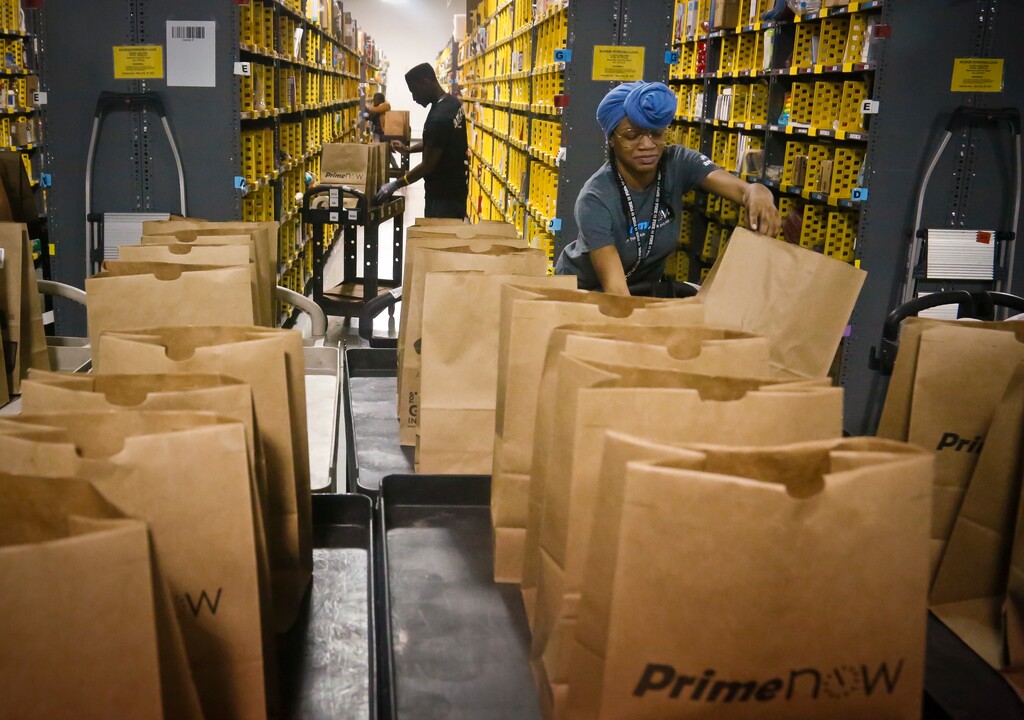 FILE - In this Wednesday Dec. 21, 2016, file photo, Miracle Stewart, right, an employee of Amazon PrimeNow, prepares bags to fill with orders from customers making purchases, at a distribution hub in New York. Amazon said Thursday, Jan. 12, 2017, that it plans to hire 100,000 people across the U.S. over the next 18 months. The online retailer says they are full-time jobs that come with benefits. Many of the jobs will be at new fulfillment centers being built in several states, including California, Florida and Texas. (AP Photo/Bebeto Matthews, File)
