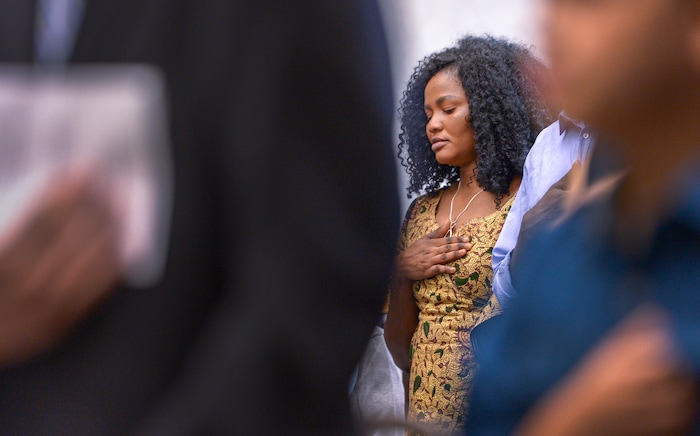Leah Hogsten | The Salt Lake Tribune With a hand on her heart, Julius Charles closes her eyes during the Pledge of Allegiance as her son, Andrew Charles and other youth representing 8 countries, take the oath of citizenship as America's newest citizens during a youth naturalization ceremony at the Viridian Event Center in West Jordan, Monday, August 6, 2018.