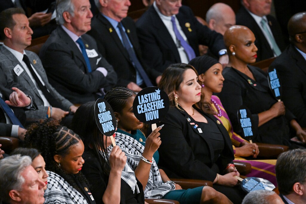 (Kenny Holston | The New York Times) Democratic representatives hold signs that read "stop sending bombs" as President Joe Biden talks about the Israel-Gaza conflict during the State of the Union address at the U.S. Capitol in Washington, on March 7, 2024.