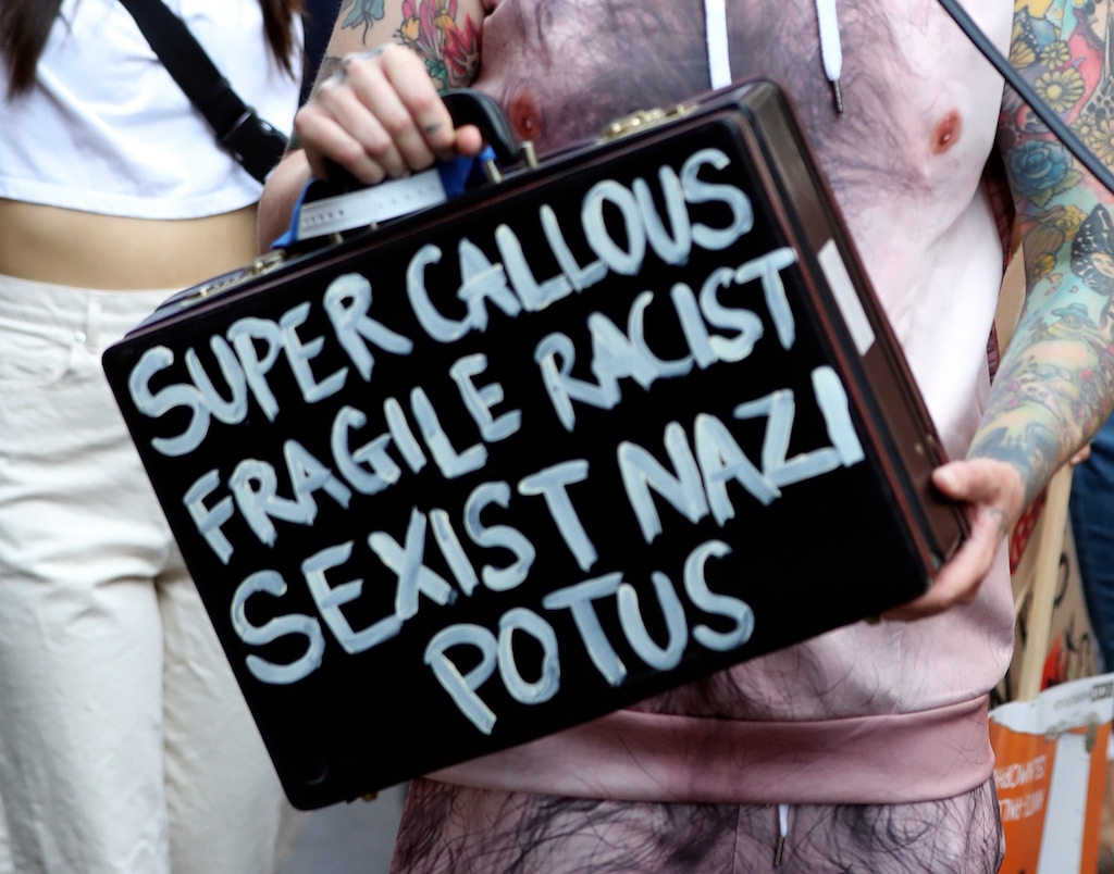 A protester holds a suitcase bearing a message at the 'Stop Trump' Women's March in London, Friday, July 13, 2018. "Super Callous Fragile Racist Sexist Nazi POTUS”: That placard, referencing Mary Poppins, is just one of the many humorous and creative signs seen at the huge rallies protesting U.S. President Donald Trump’s visit to Britain. Huge crowds poured into London’s streets Friday to protest Trump’s policies, from immigration to race relations to women and climate change.  (Gareth Fuller/PA via AP)