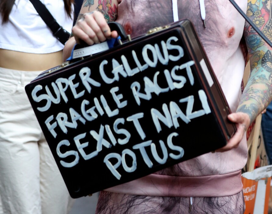 A protester holds a suitcase bearing a message at the 'Stop Trump' Women's March in London, Friday, July 13, 2018. "Super Callous Fragile Racist Sexist Nazi POTUS”: That placard, referencing Mary Poppins, is just one of the many humorous and creative signs seen at the huge rallies protesting U.S. President Donald Trump’s visit to Britain. Huge crowds poured into London’s streets Friday to protest Trump’s policies, from immigration to race relations to women and climate change.  (Gareth Fuller/PA via AP)