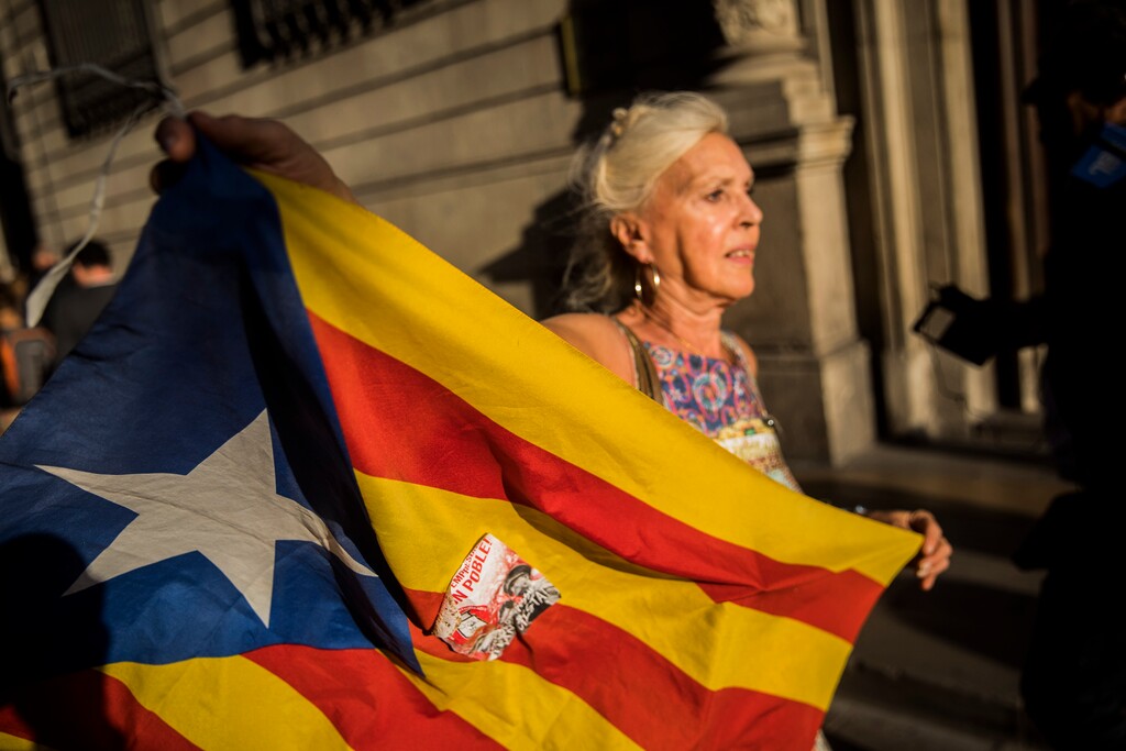 (AP Photo/Santi Palacios) A woman waves an independence flag just after the speech of Catalan regional president Carles Puigdemont in Barcelona, Spain, Thursday, Oct. 26, 2017. Puigdemont said Thursday he considered calling a snap election, but was choosing not to because he didn't receive enough guarantees that the government's "abusive" moves to take control of Catalonia would be suspended.