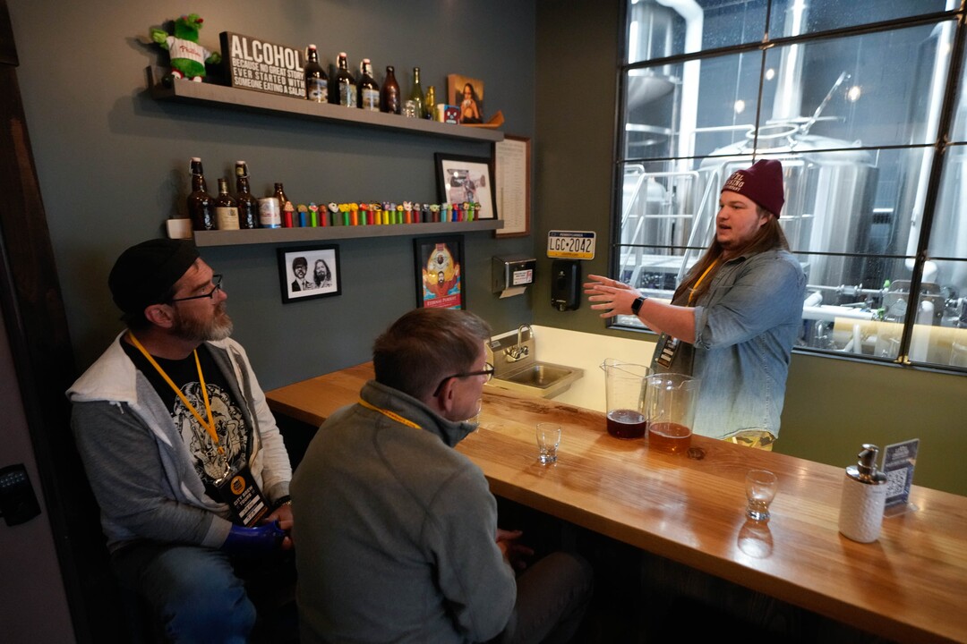 (Francisco Kjolseth | The Salt Lake Tribune) City Brew Tours in Salt Lake guide Liam Bice, right, gives Dane Hofmann, left, and Charley Ellis a behind the scenes look at the process at Level Crossing Brewery on Saturday, April 30, 2022. The new educational beer tour takes folks around to local breweries to see the back end brewing process, sample beers and pair them with food. 