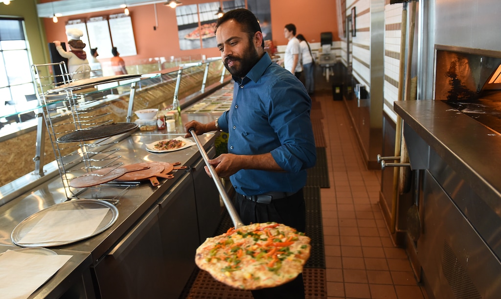 (Francisco Kjolseth  |  The Salt Lake Tribune)  Bhinda Singh, owner of Curry Pizza, a new restaurant in West Valley City, pulls out a freshly cooked pizza. Singh has combined Italy's classic meal with the flavors and spices of India.