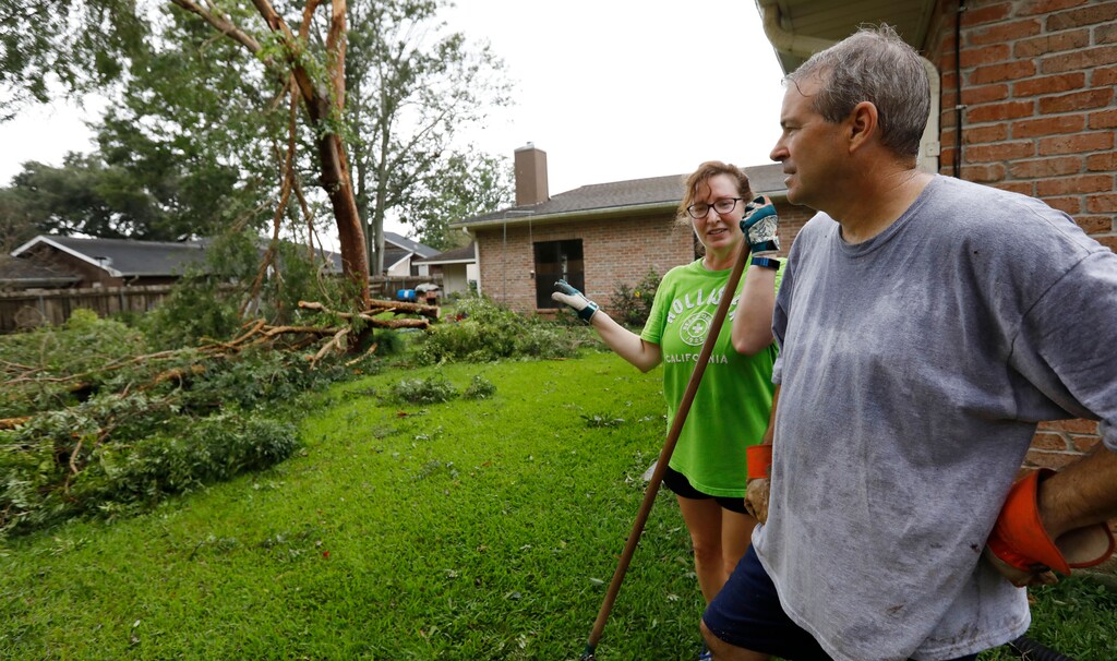 (Rogelio V. Solis | AP) "At least it did not hit the house," says Lois Bergeron, left, Sunday, July 14, 2019, as she and her husband Steve Bergeron take a break from cleanup after Tropical Storm Barry and look at their downwd backyard tree, in Morgan City, La.