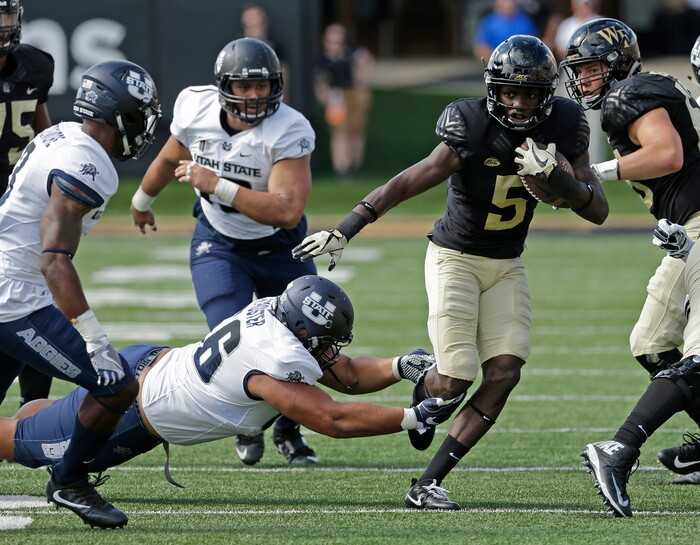 Wake Forest's Arkeem Byrd (5) runs past Utah State's Gasetoto Schuster (56) in the first half of an NCAA college football game in Winston-Salem, N.C., Saturday, Sept. 16, 2017. (AP Photo/Chuck Burton)