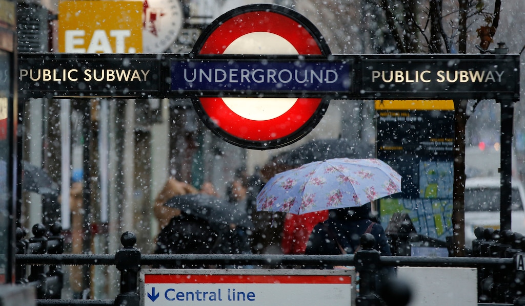 A woman walks away from Notting Hill underground station as snow falls in London Sunday, Dec.10, 2017. (AP Photo/Alastair Grant)