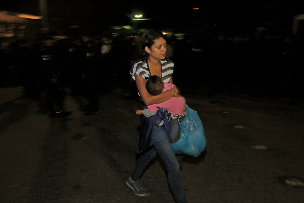 A Honduran migrant carries a baby as she enters Guatemala at the border crossing in Agua Caliente, Guatemala, Tuesday, Jan. 15, 2019. The latest caravan of Honduran migrants hoping to reach the U.S. has crossed peacefully into Guatemala, under the watchful eyes of about 200 Guatemalan police and soldiers. (AP Photo/Moises Castillo)