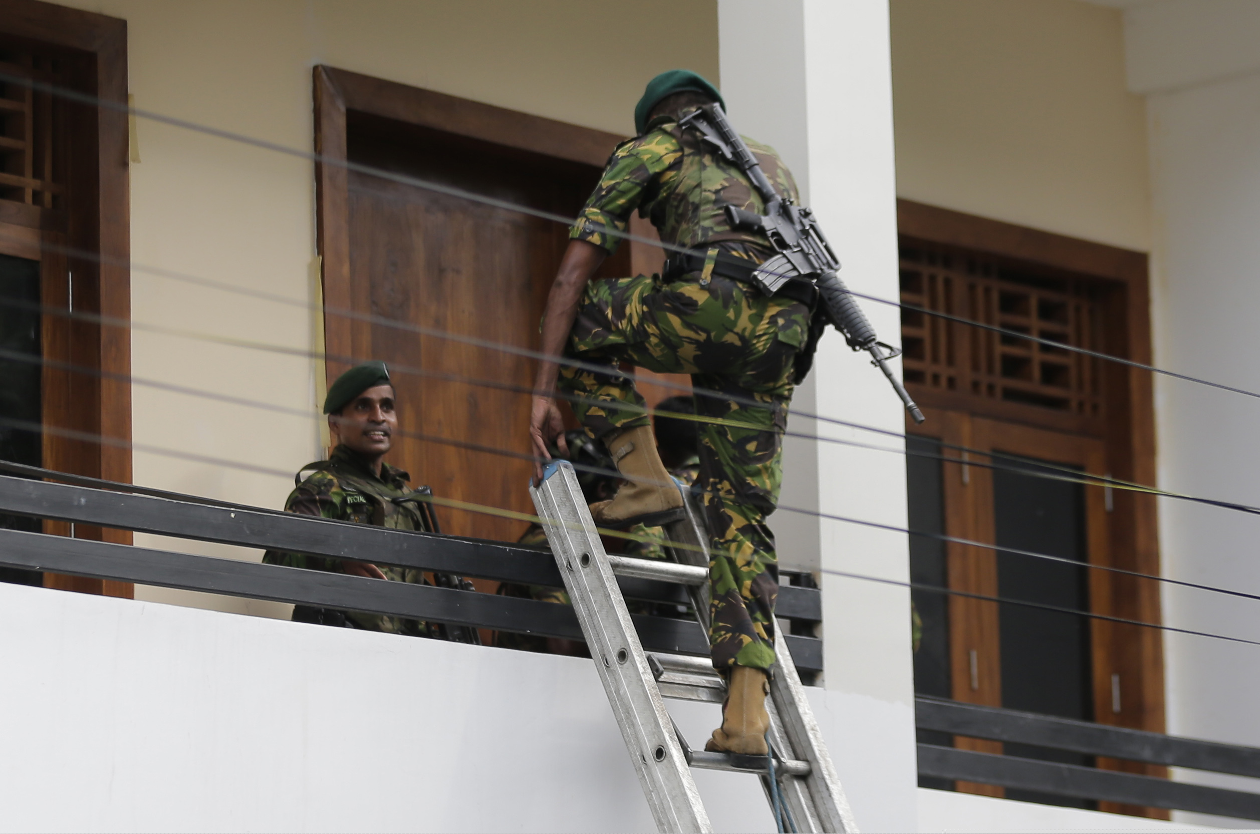 A Sri Lankan police commando enters a house suspected to be a hideout of militants following a shoot out in Colombo, Sri Lanka, Sunday, April 21, 2019.  More than hundred were killed and hundreds more hospitalized with injuries from eight blasts that rocked churches and hotels in and just outside of Sri Lanka's capital on Easter Sunday, officials said, the worst violence to hit the South Asian country since its civil war ended a decade ago. (AP Photo/Eranga Jayawardena)