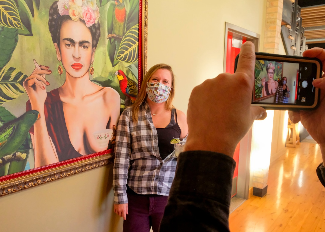 (Leah Hogsten  |  The Salt Lake Tribune) Sarah Carney, an art teacher from Virginia poses for a photo with a painting of painter Frida Kahlo as Stephen Ysebaert takes his friend's picture. Salt Lake City's popular Rio Grande Cafe, which has been closed since March due to the pandemic and the earthquake, has moved to its new location near the University of Utah on 1300 East, Dec. 29, 2020.